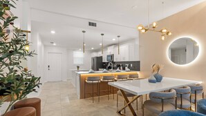 A modern kitchen with white cabinets, a central island with bar stools, and pendant lighting.