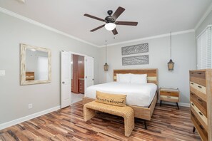 A bedroom with a bed, a nightstand, a dresser, a ceiling fan, and a mirror. - Spacious Mid Term Rental! University City Home with Game Room, Huge Fenced Yard, Pets OK +20% Off! (Charlotte)