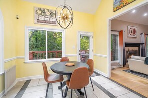 A dining area with a round table and chairs, a chandelier, and a view of greenery outside. - Spacious Mid Term Rental! University City Home with Game Room, Huge Fenced Yard, Pets OK +20% Off! (Charlotte)