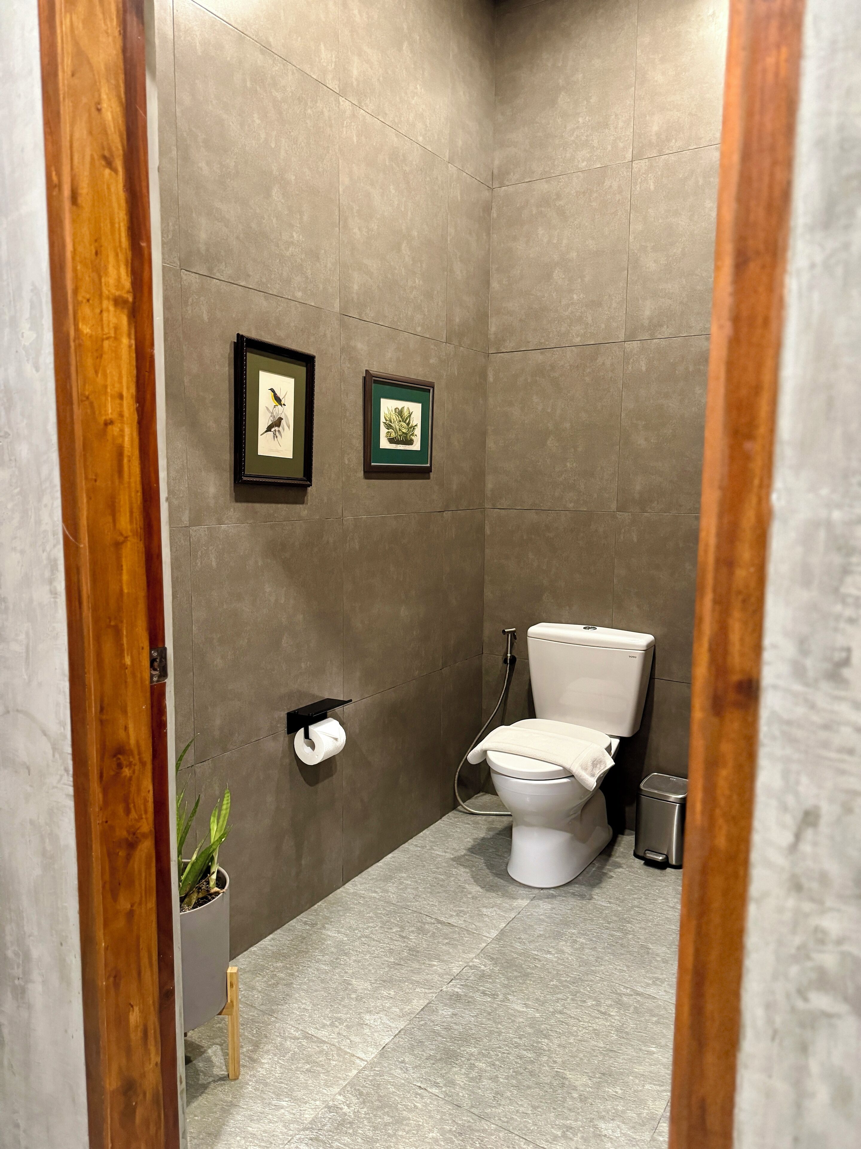 Ein modernes Badezimmer mit Toilette, einer kleinen Mülltonne und zwei gerahmten Bildern an der Wand.