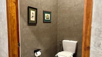 Ein modernes Badezimmer mit Toilette, einer kleinen Mülltonne und zwei gerahmten Bildern an der Wand.