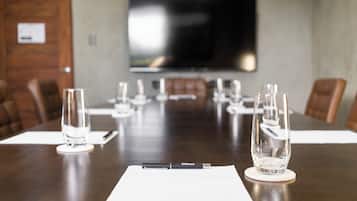 A conference room with a long table, chairs, a TV screen, and a pen on a notepad.