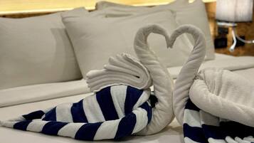 Una cama bien tendida con sábanas blancas y dos toallas con forma de cisnes.