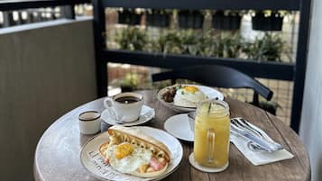 Una mesa redonda de madera con un desayuno que incluye un plato de huevos, una taza de café y un vaso de jugo.