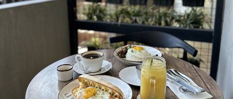 Una mesa redonda de madera con un desayuno que incluye un plato de huevos, una taza de café y un vaso de jugo.