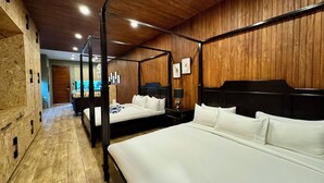 A four-poster bed with white linens, a wooden floor, and a wooden-paneled wall with framed pictures. - Hotel Dumaguete (Dumaguete)