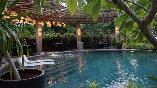 A pool area with a pergola, lounge chairs, and a dining table. - Hotel Dumaguete (Dumaguete)