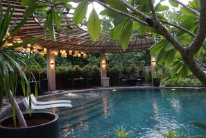 A pool area with a pergola, lounge chairs, and a dining table. - Hotel Dumaguete (Dumaguete)