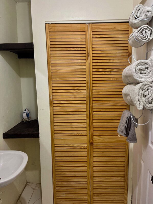 Une salle de bain avec une armoire en bois, un lavabo et des serviettes accrochées au mur.