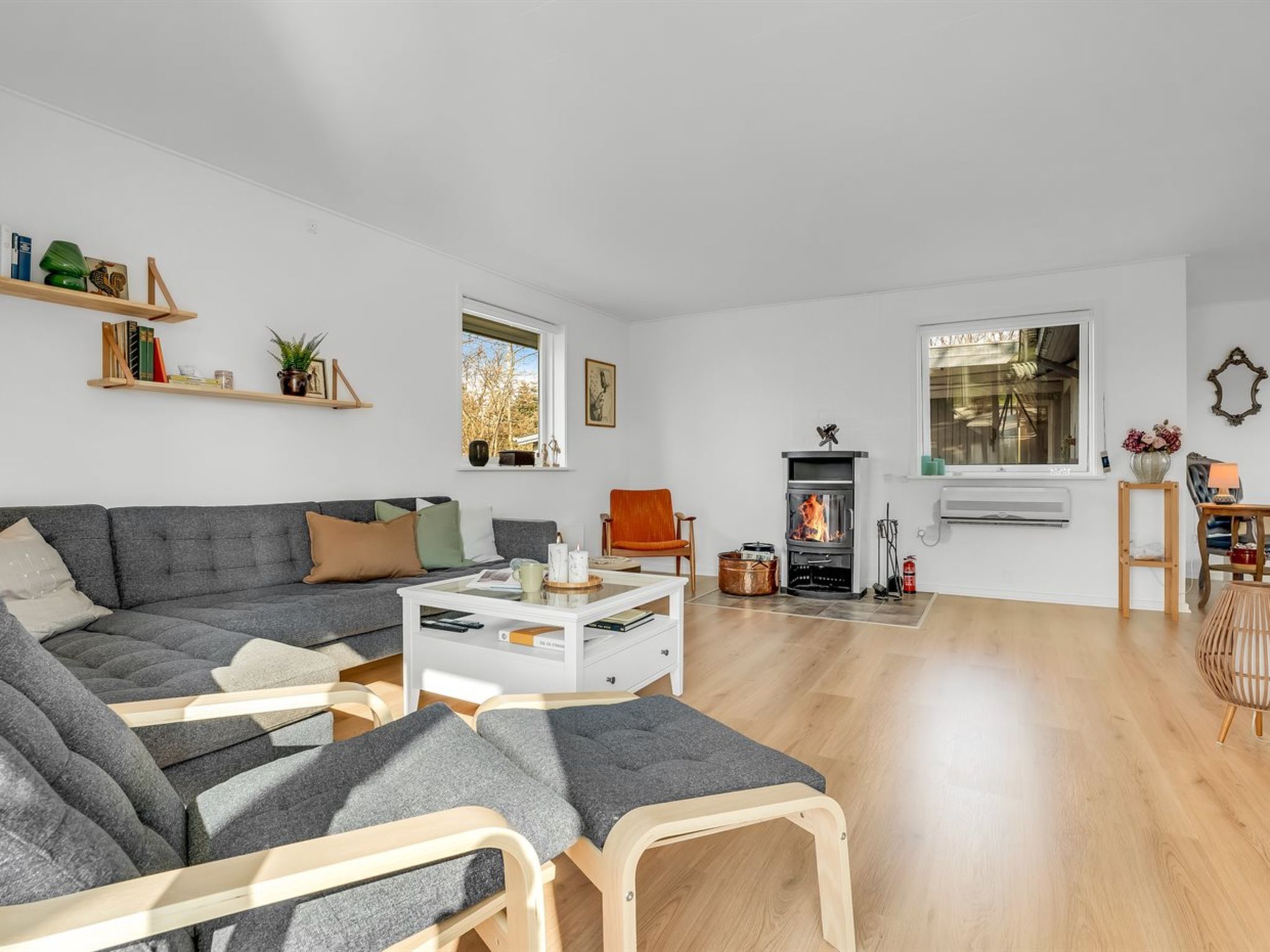 A modern living room with a grey sectional sofa, a white coffee table, and a fireplace.