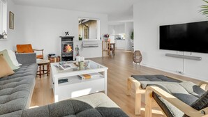 Een moderne woonkamer met een open haard, een bank, salontafel en een televisie.