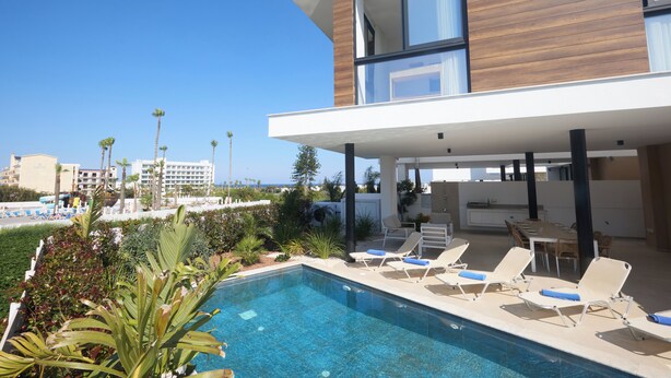 A modern house with a pool, lounge chairs, and a dining area. - Protaras Aqua Pearl Villa AQ01 (Protaras)