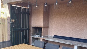 An outdoor patio with a wooden table and chairs, a grill, and string lights. - St Cyprien superb house residence with swimming pool (Saint-Cyprien)