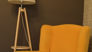 A yellow armchair with a cushion, a floor lamp, and a brick wall. - Middle Asia Deer Cave in Urban City (Almaty)
