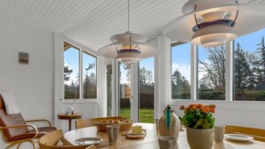 A dining area with a wooden table, chairs, and a vase of flowers. - "Andrine" - 100m from the sea by Interhome (Nakskov)