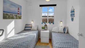 A bedroom with two beds, a window with a view, a painting of a lighthouse, and a wall decoration. - "Andrine" - 100m from the sea by Interhome (Nakskov)