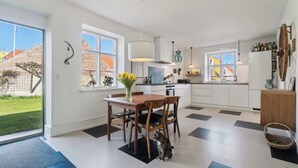 Une cuisine moderne avec une table à manger, des chaises et un chat assis sur le sol.