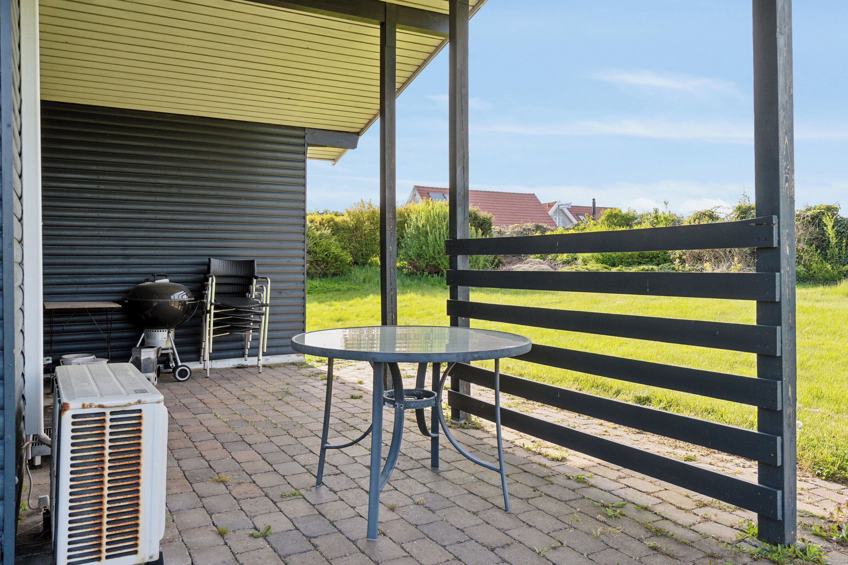 Eine Terrasse mit Tisch und Stühlen, einem Grill und einer Klimaanlage.