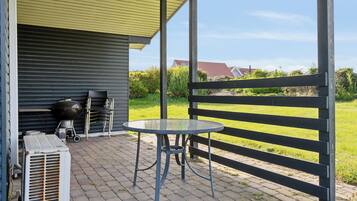 Eine Terrasse mit Tisch und Stühlen, einem Grill und einer Klimaanlage.