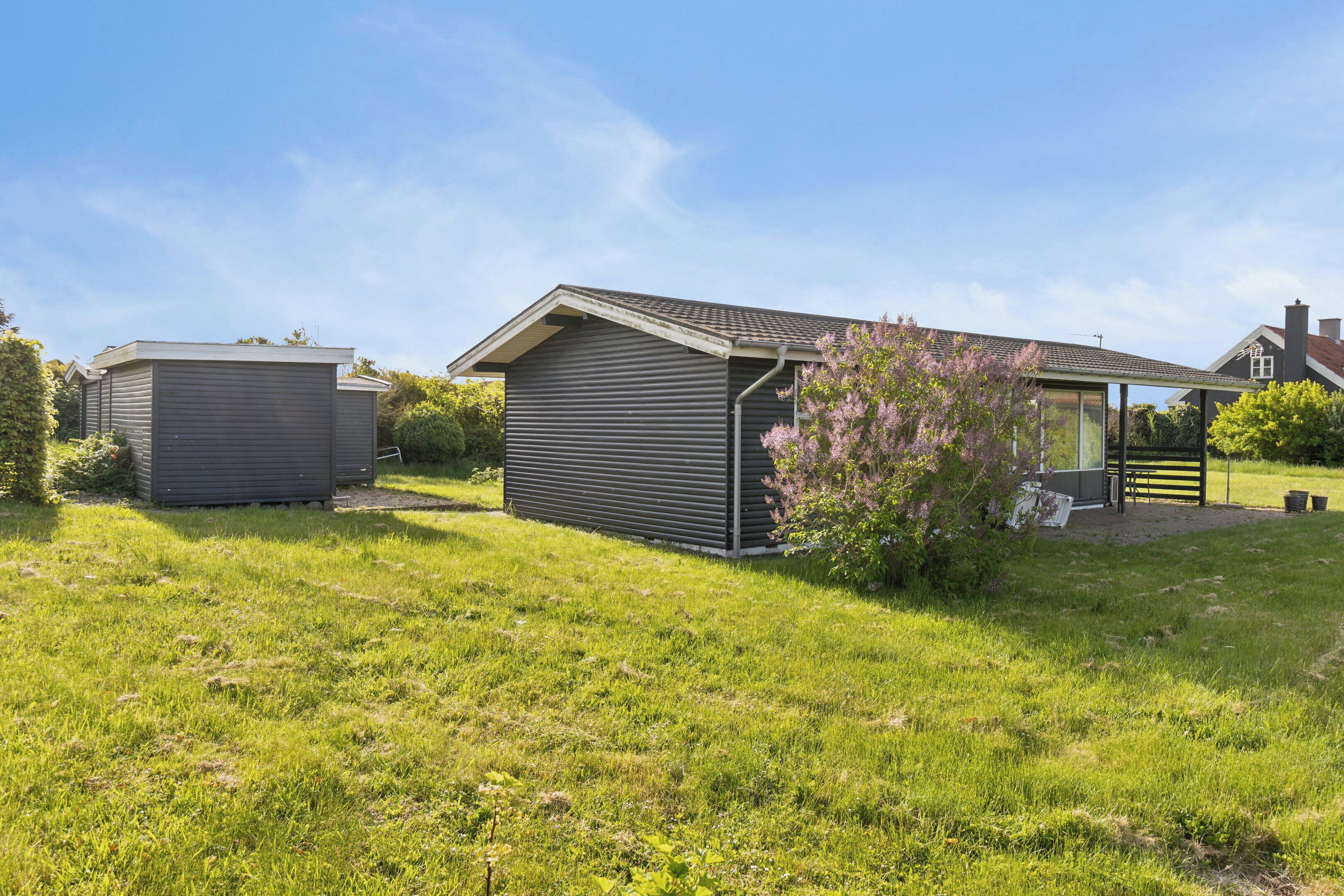 A residential property with a detached house, a garage, and a covered outdoor area.