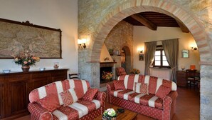 Un accogliente soggiorno con camino in pietra, due divani decorati, un mobiletto in legno e una grande mappa appesa al muro.