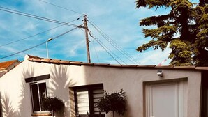 A building with a tiled patio, two potted plants, a white door, and a window with a shutter. - Le cabanon du Cannet.charming, fully-equipped two-room apartment close to amenities. (Le Cannet)