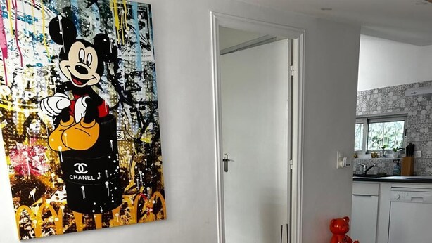 A living room with a sofa, a colorful artwork, a small table, and a chair. - Le cabanon du Cannet.charming, fully-equipped two-room apartment close to amenities. (Le Cannet)