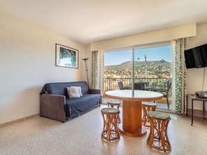 Relax in a serene space with a comfortable sofa, round table, and scenic views of the hilly landscape.