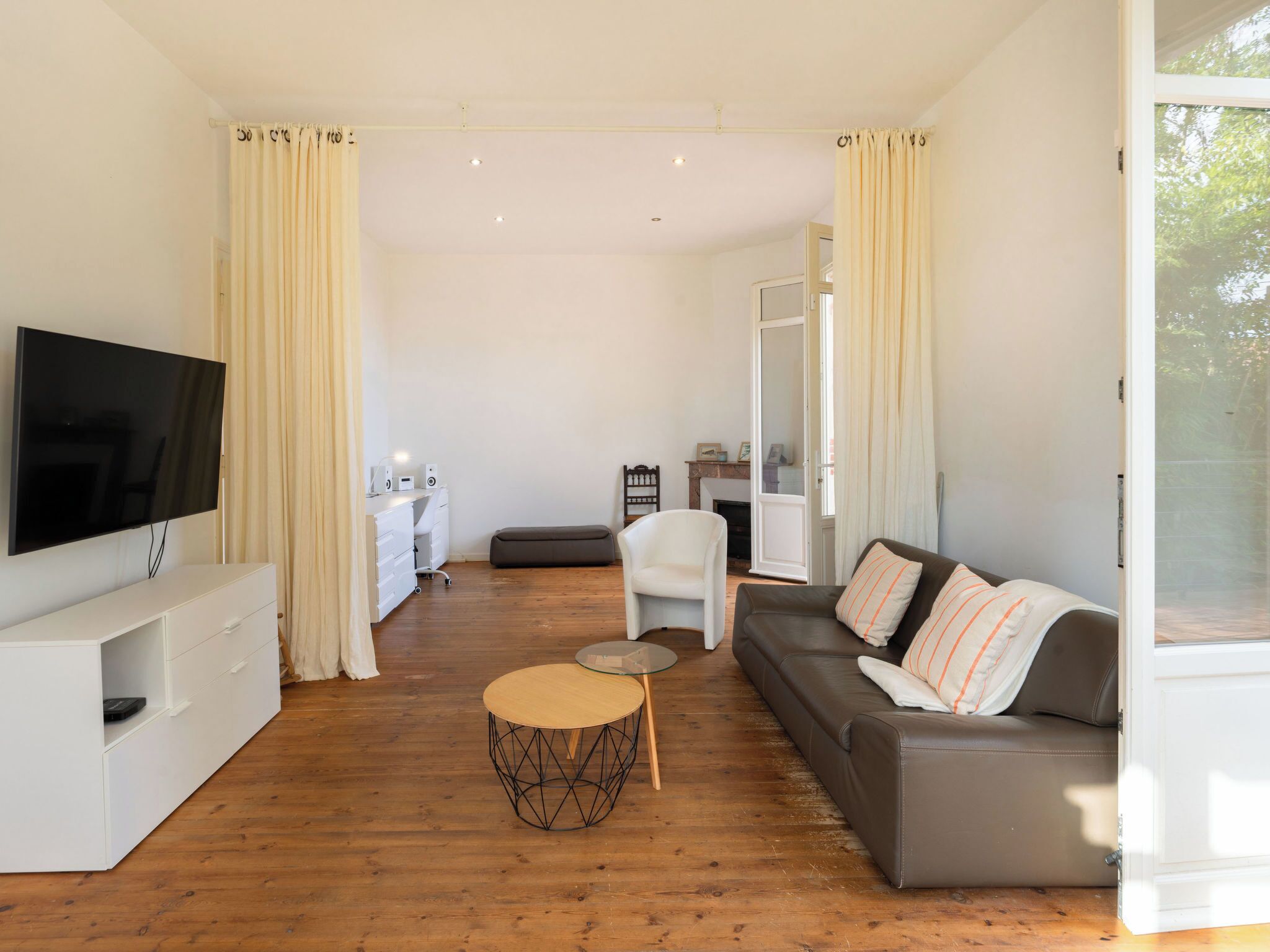 A modern living room with a flat-screen TV, a sofa, a coffee table, and a desk with a chair.
