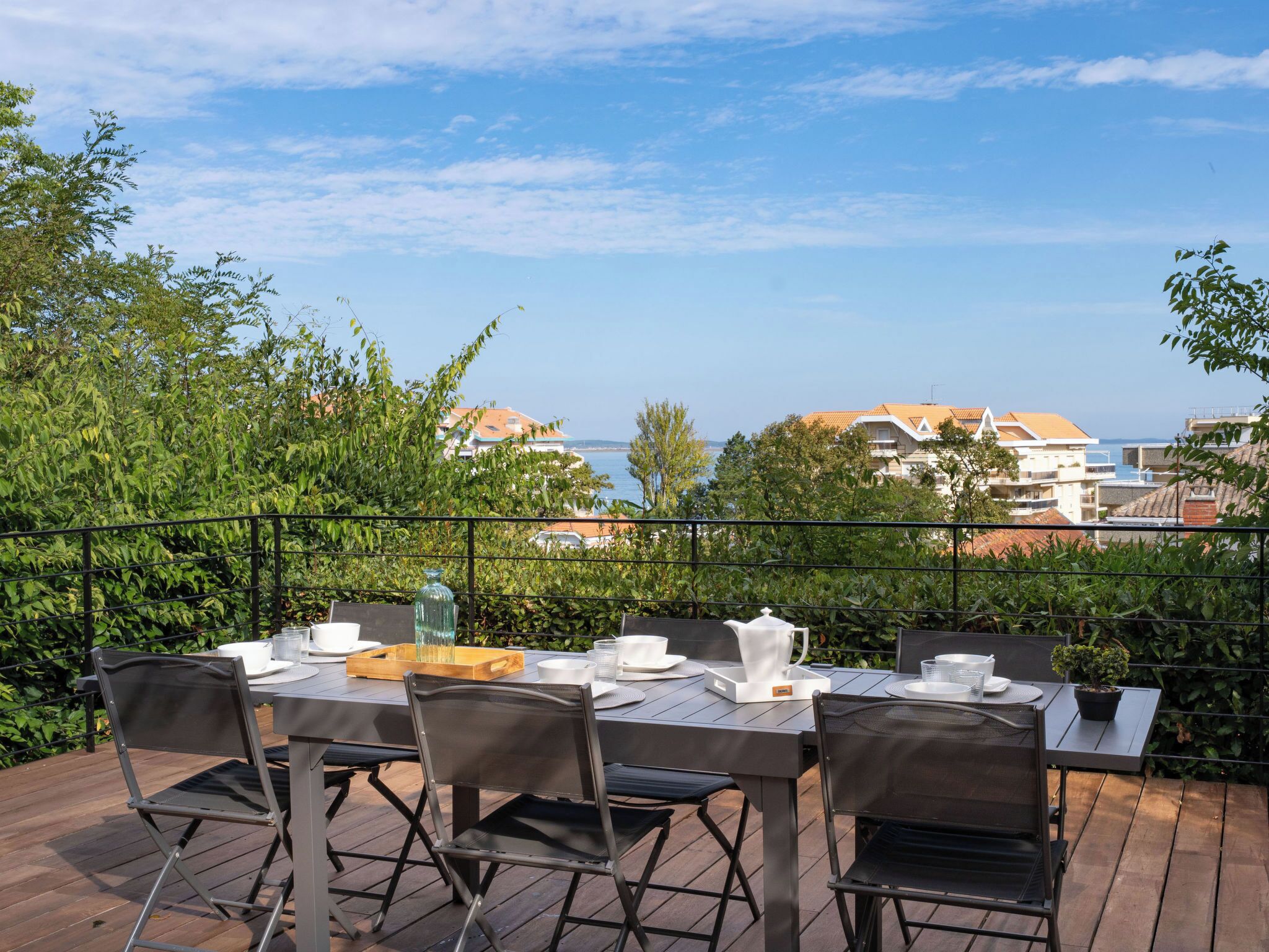 An outdoor dining area with a view of the sea and buildings.