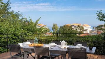 An outdoor dining area with a view of the sea and buildings.
