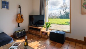 A living room with a guitar, TV, and a large window with a view of a green field. - Feliz Breizh by Interhome (Plounevez Lochrist)