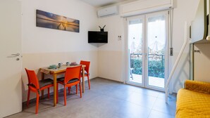 Un espace de vie compact comprenant un coin repas, un lit, un téléviseur et un balcon avec vue.