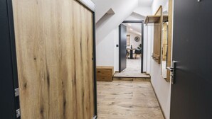 A narrow hallway with wooden flooring and a sloped ceiling.