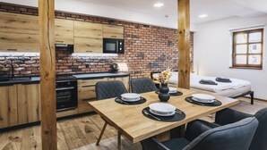 A modern kitchen with a brick backsplash, wooden cabinets, and a dining area with a wooden table and chairs.