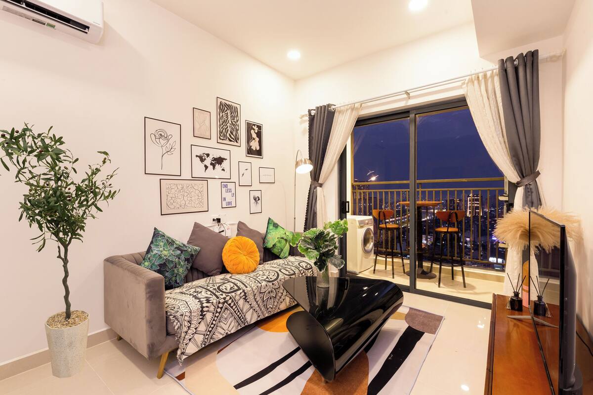 Un salon moderne avec un canapé, un téléviseur et un balcon offrant une vue sur la ville.