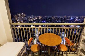 Ein Balkon mit Tisch und Stühlen mit Blick auf eine nächtliche Skyline.