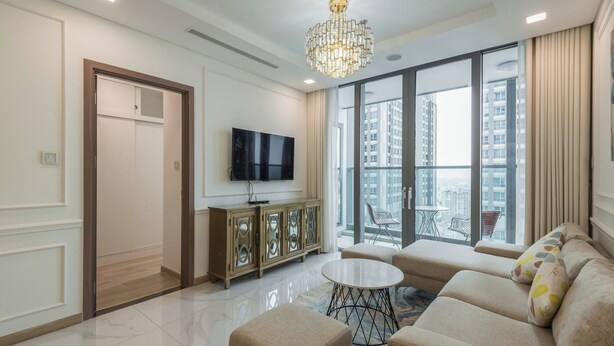 A modern living room with a flat-screen TV, a chandelier, a sofa set, and a large window offering a city view. - Sunwah Pearl Centre Point (Ho Chi Minh City)