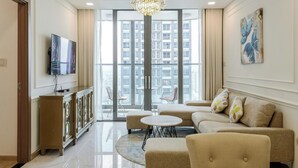 A modern living room with a sofa, a coffee table, a TV, and a chandelier. - Sunwah Pearl Centre Point (Ho Chi Minh City)
