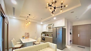 Una cocina moderna con refrigerador integrado, un comedor con mesa y sillas blancas, y un sofá beige en la sala.