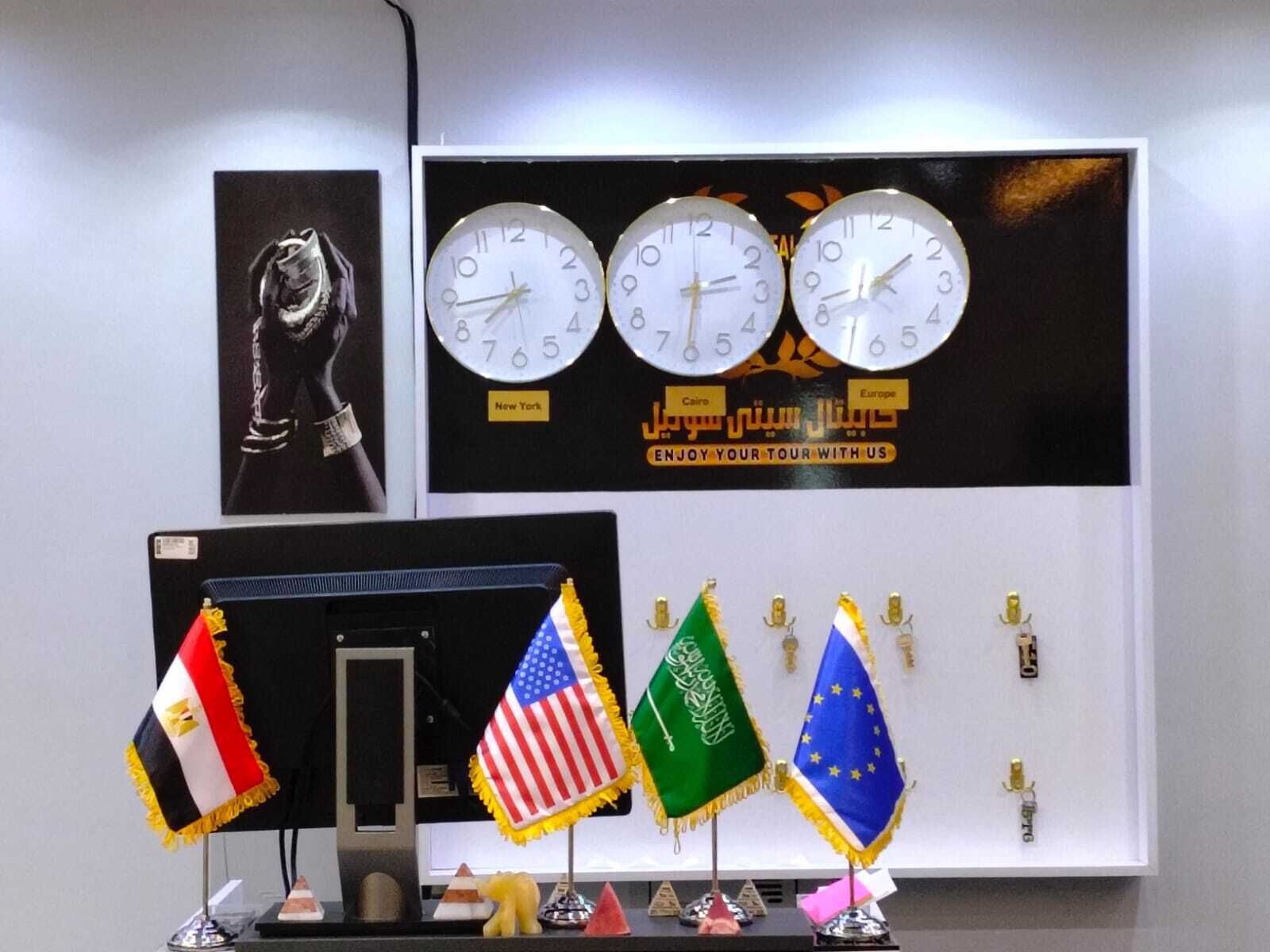 A wall with clocks, flags, and a framed picture.