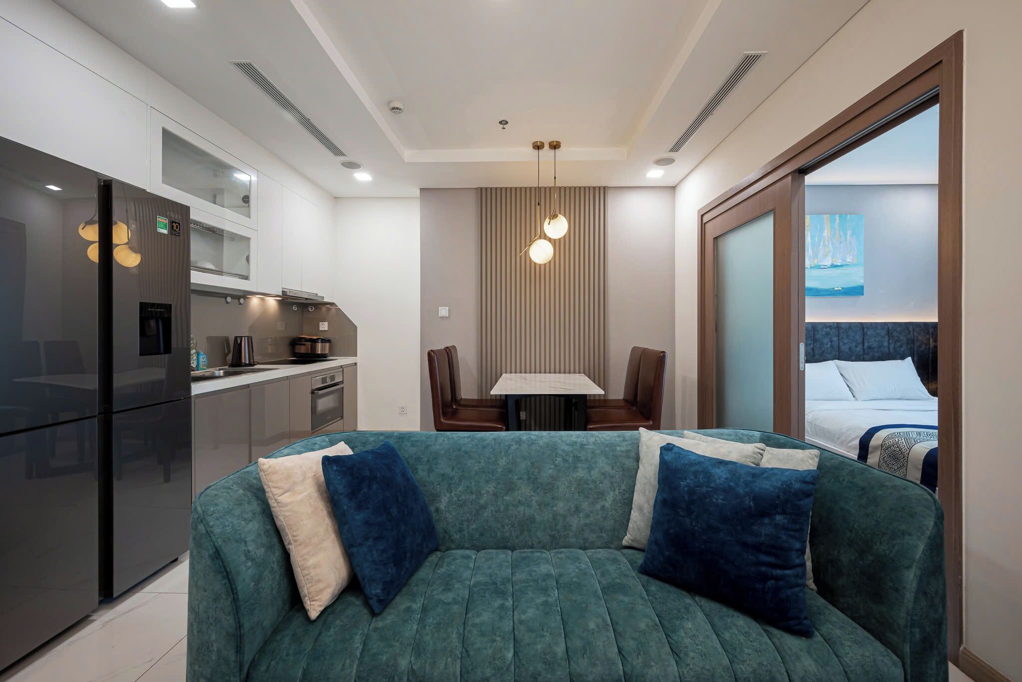 A modern living area with a sofa, a dining table, and a kitchen in the background.