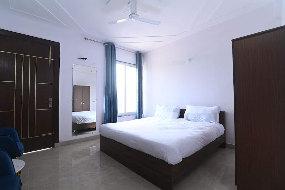 A bedroom with a bed, a wardrobe, a ceiling fan, and a window with curtains.