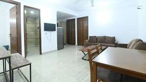 A spacious living area with a dining table, sofas, and a TV mounted on the wall. - Ima Retreat (New Delhi)