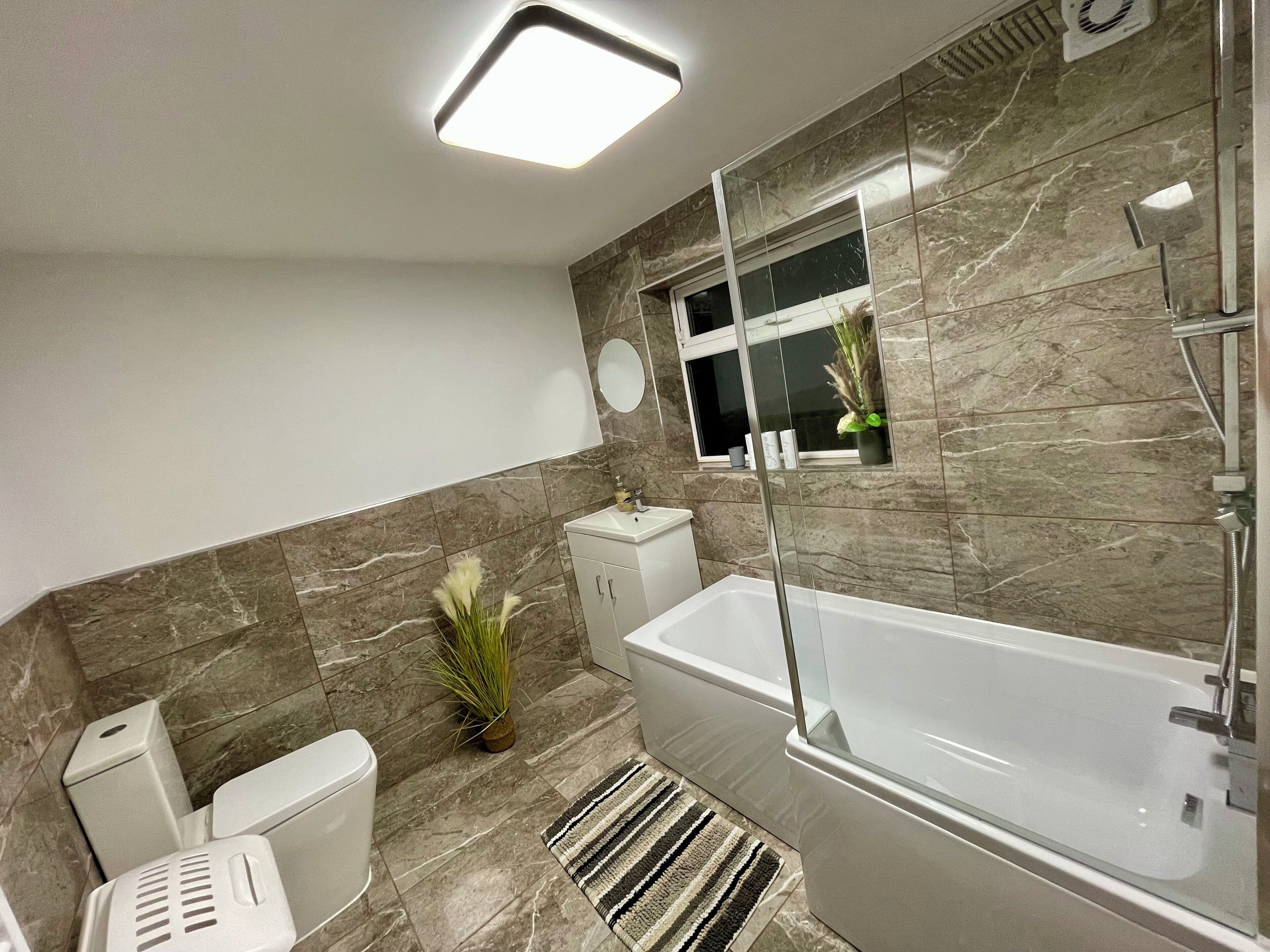 A modern bathroom with a bathtub, toilet, and sink.