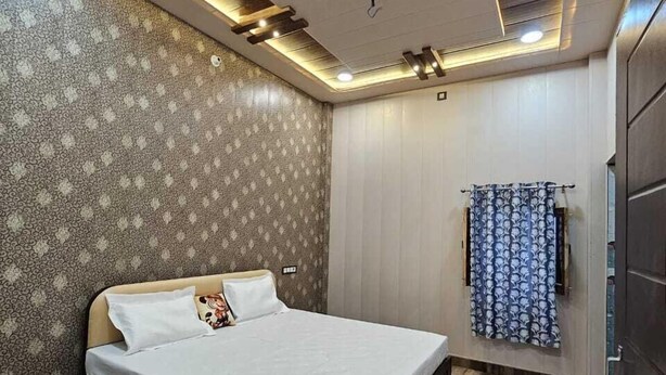 A bedroom with a bed, patterned wallpaper, a curtain, and a wooden floor. - Vinayak Guest House  (Faizabad)