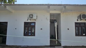 A two-story building with a white exterior, two air conditioning units, and a narrow entrance. - Vinayak Guest House  (Faizabad)