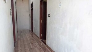 A narrow hallway with wooden flooring and white walls. - Vinayak Guest House  (Faizabad)