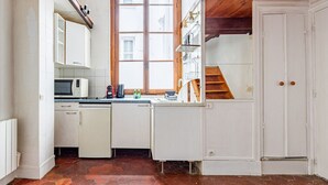 A compact kitchen with white cabinets, a microwave, a sink, and a window with a view.