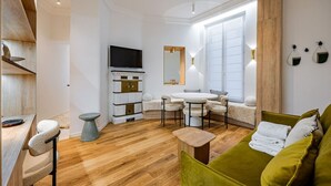 Een moderne woonkamer met een bank, stoelen, een televisie, een open haard en een eethoek.